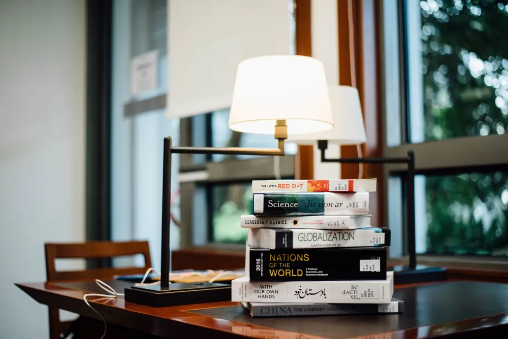 Pila de libros apilados junto a una lampara de lectura, referencia al contenido de cultura pop y libros en Instagram Mexico