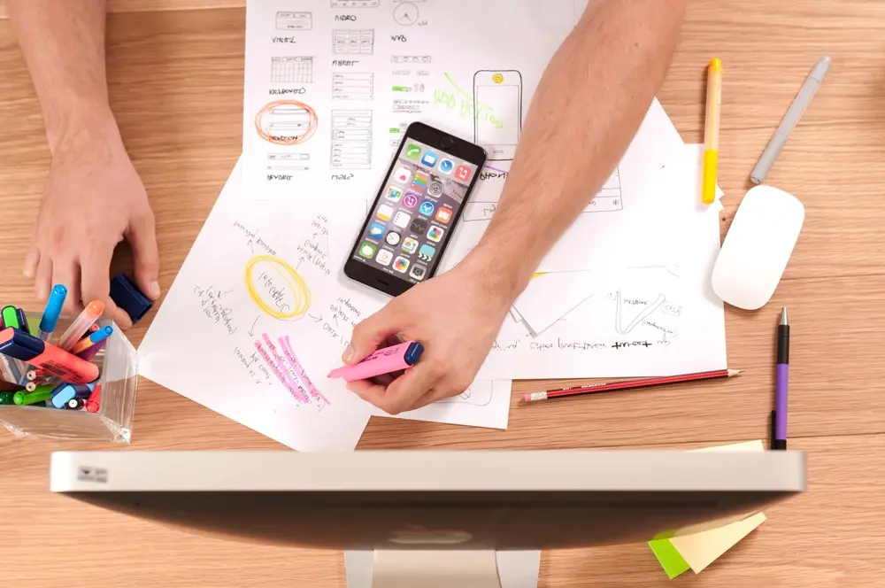 Escritorio con celular, bocetos de apps y marcadores, referencia al trabajo de social media manager en Instagram México