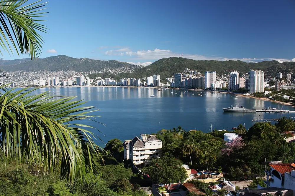 Vista de la bahía de Acapulco con palmeras y edificios frente al mar, referencia al contenido lifestyle de Instagram en México